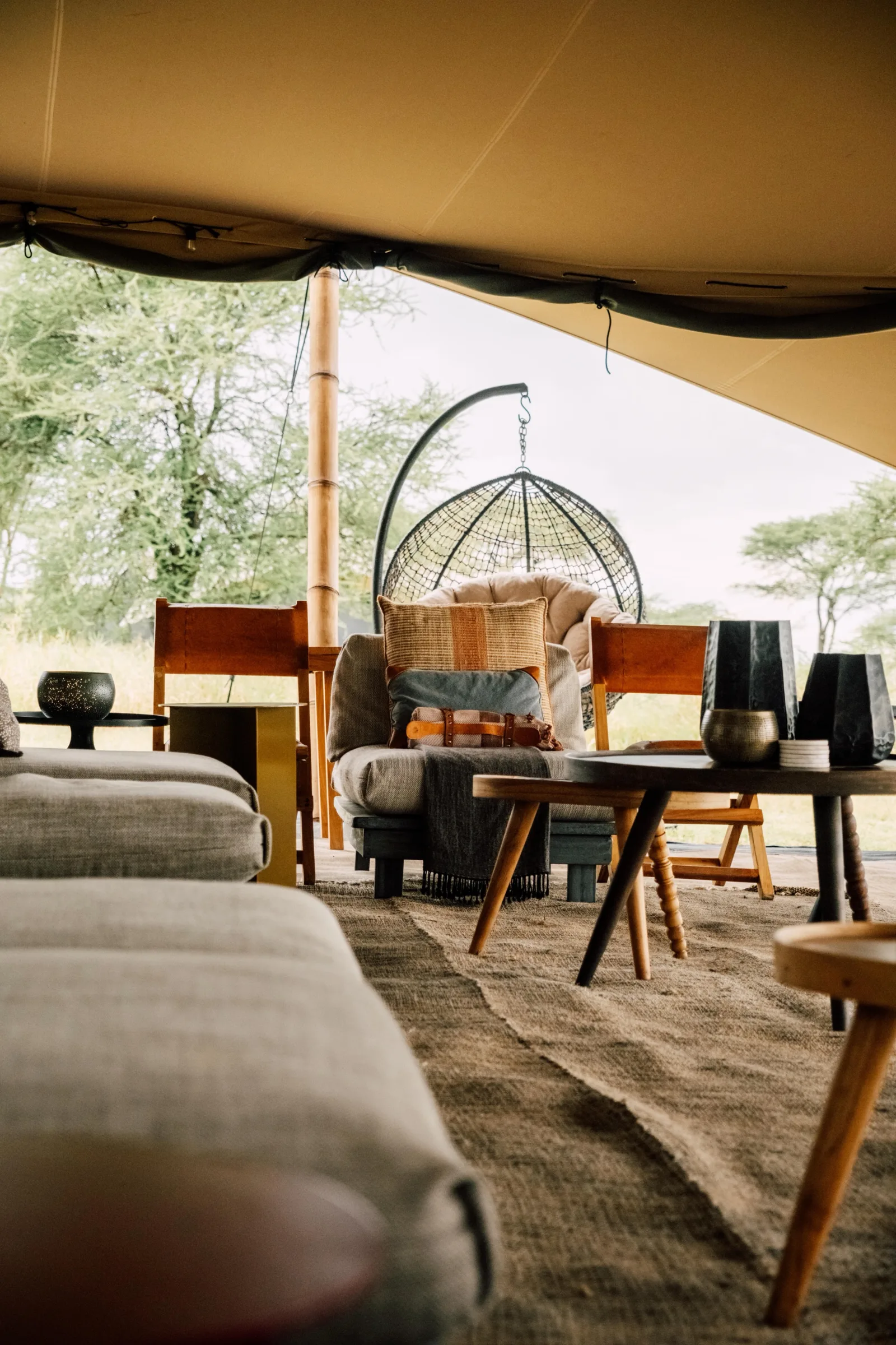Before: Safari-Tent-Lounge mit hängendem Rattan-Egg-Chair und Blick zur Akazien-Savanne